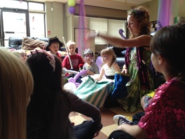 A woman with fairy wings entertains a crowd of children by doing a magic trick