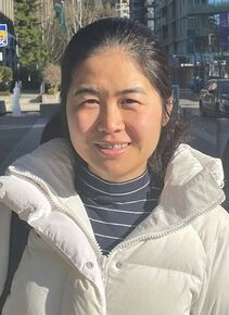 A woman wearing a white puffy jacket smiles at the camera