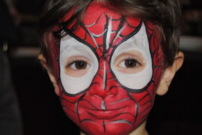 Red and while Spider-man face paint on a little boy